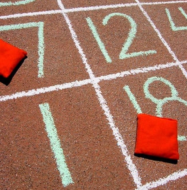 bean-bag-toss-subtraction A grid of numbers written in chalk on the sidewalk with red bean bags in some squares