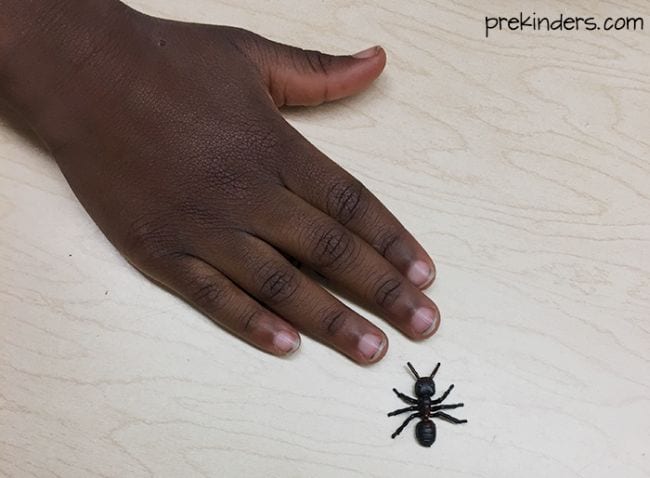 subtraction-game A child's hand laid flat on a table next to a plastic spider