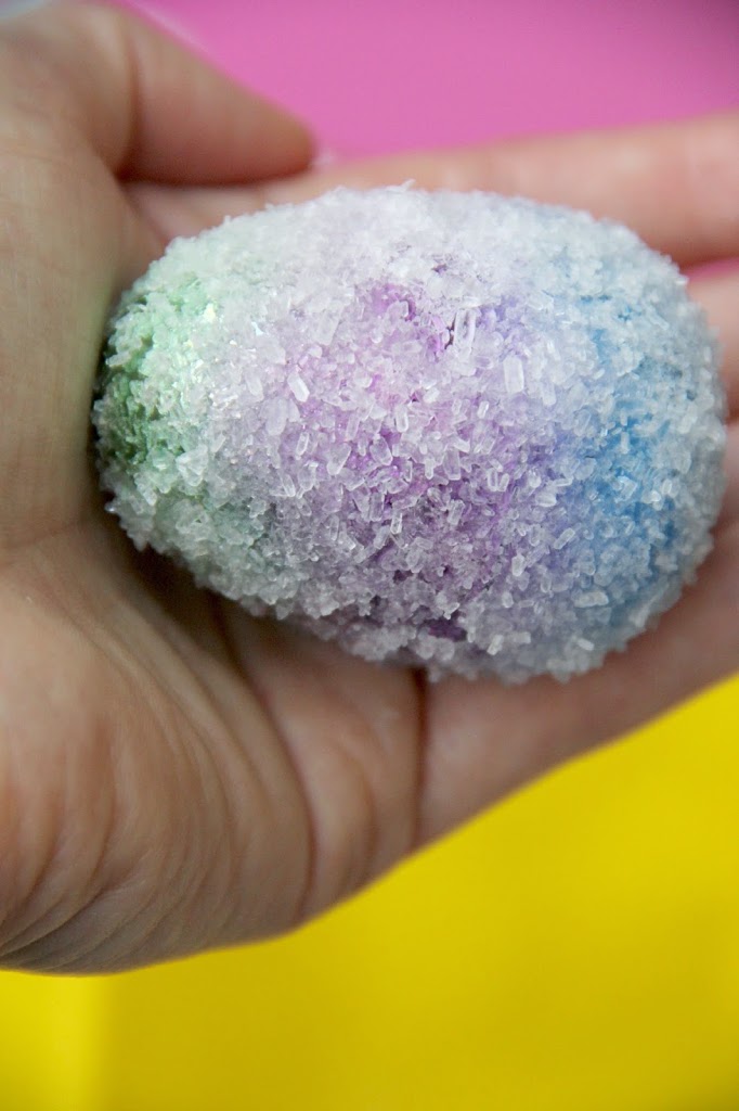 crystal-egg hand holding an egg colored and covered in borax for a plastic egg activity