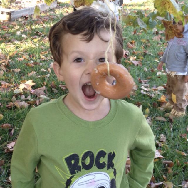 Donut on a String Minute to win it games include eating a donut hanging from a string like the little boy pictured here.