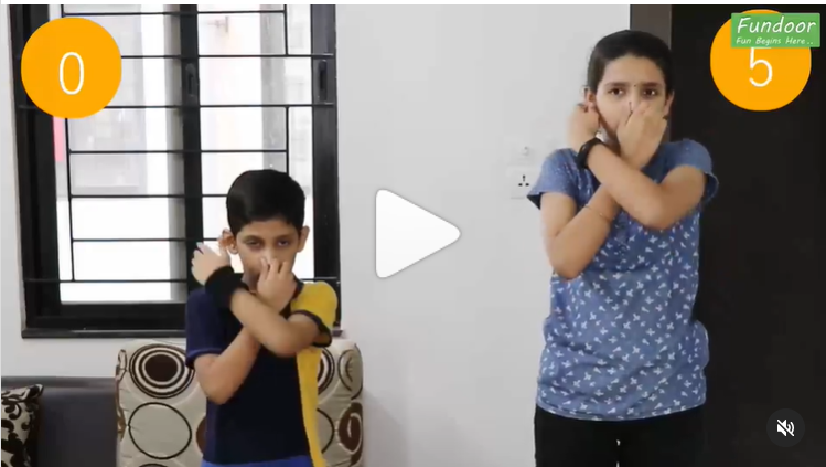 Ear Nose Pinch A little boy and girl stand with one finger pinching their ear and the other pinching their nose in this example of minute to win it games.