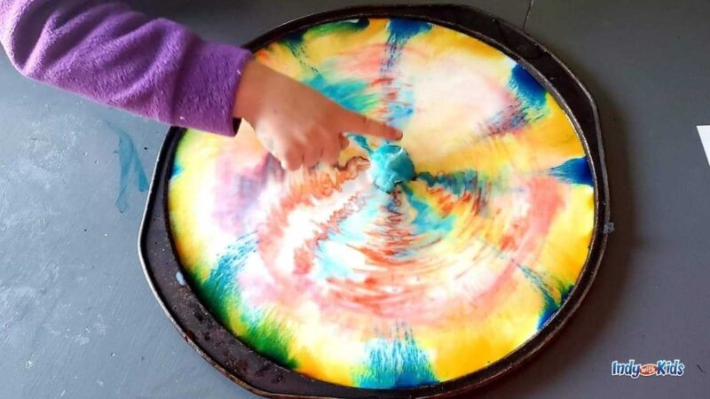 Rainbow Swirl Activity Child's finger pointing to a rainbow swirl experiment