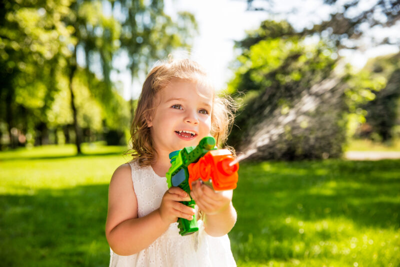 A little girl is seen shooting a water gun in this example of tag games.