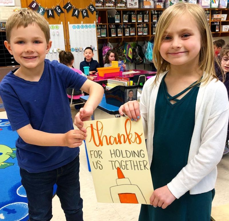 Two young students holding a sign that says 