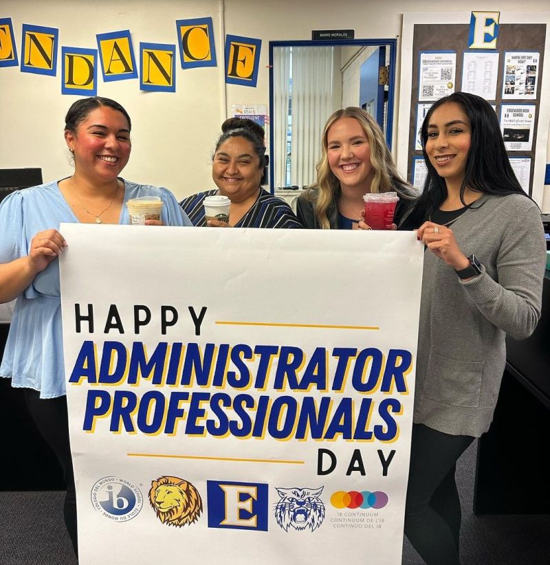 A group of school office workers standing with a sign saying 