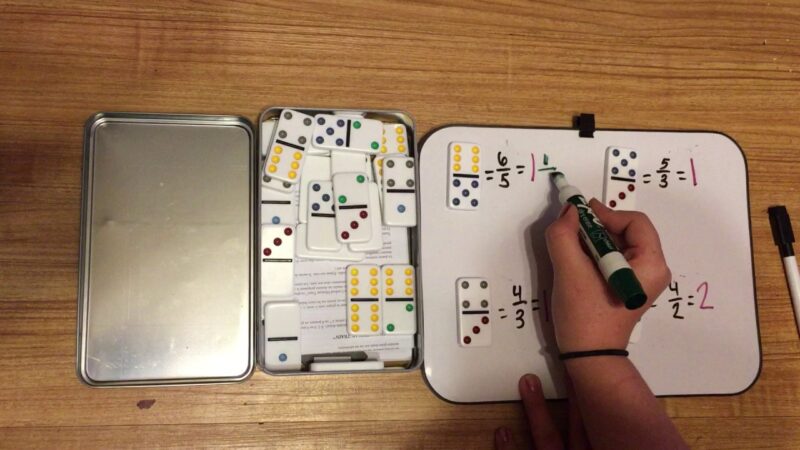 domino-fractions hand writing fraction problems on a magnetic board with dominos for teaching fractions