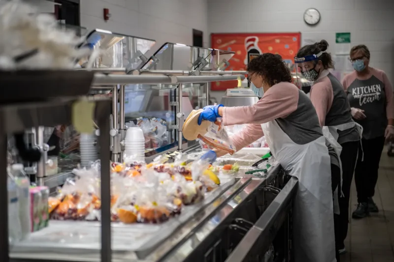 guest-server woman serving food in a cafeteria lunch line