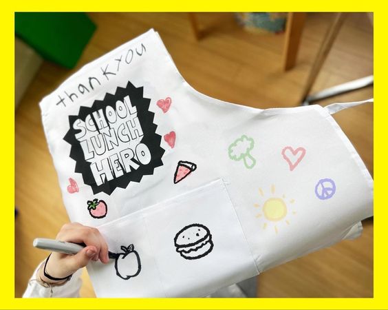 school-lunch-hero-apron white apron that is decorated with drawings in marker for school lunch hero day 2024