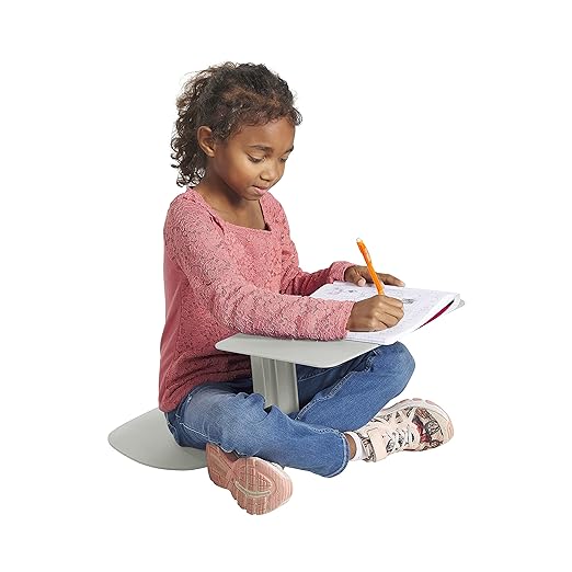 Image of young girl sitting cross-legged on ground using a lap desk