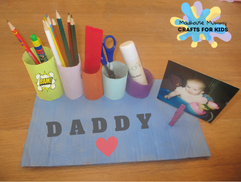 A desk organizer is made of different sized paper tubes with different colored construction paper on them.