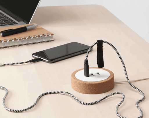 A circular charger with USB outlets is shown with a computer and phone plugged into it. 