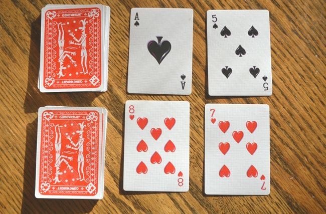 addition-war playing cards with four cards placed on a table, math facts games