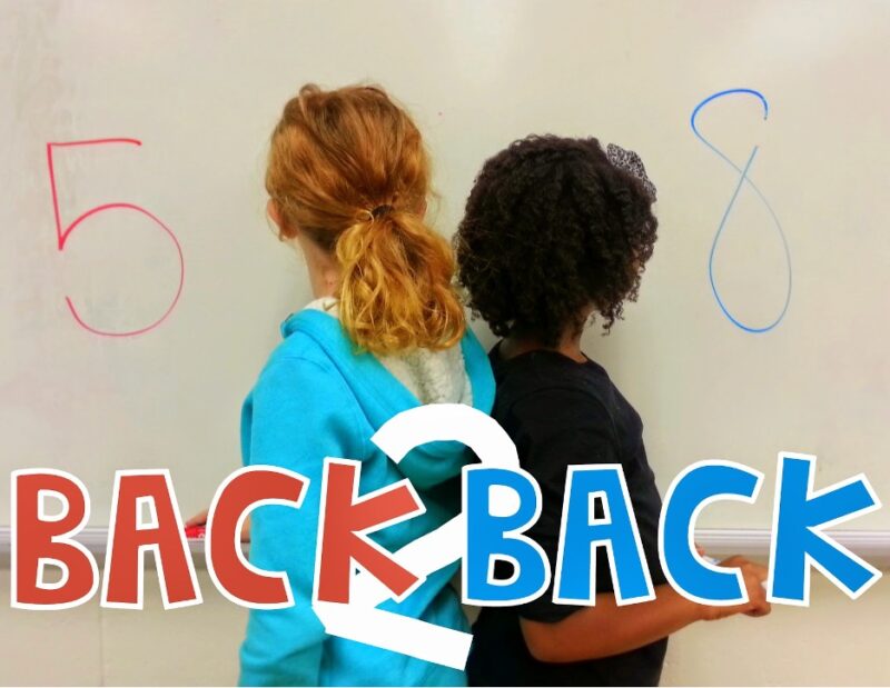 back-to-back students standing back to back writing numbers on a board
