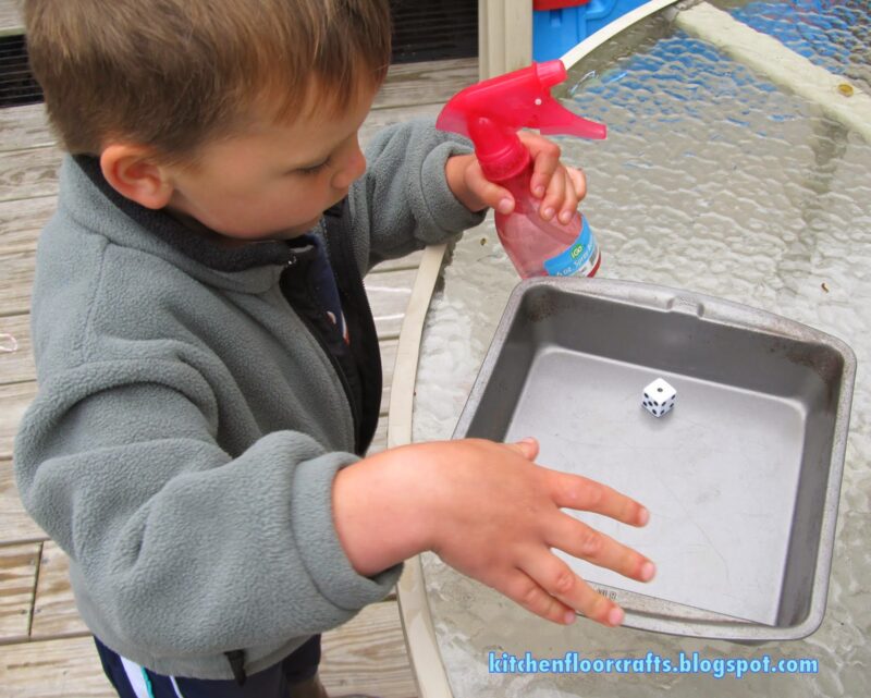 sum-spray-math-games-800×641 child holding spray bottle and looking at dice