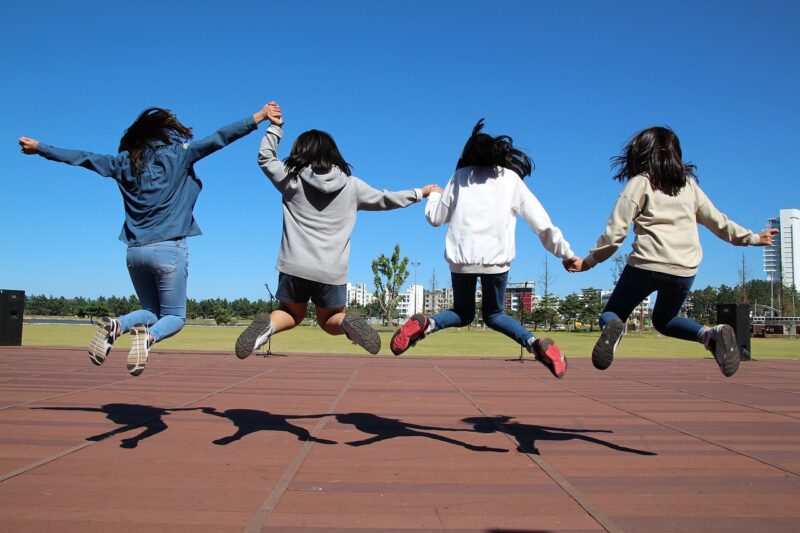Children Jumping Physical Play Four children holding hands and jumping, as an example of types of play