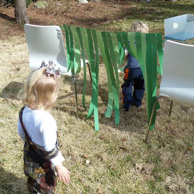 DIY Obstacle Courses for Kids: Bear Hunt Toddlers climbing through a crepe paper curtain strong across two chairs