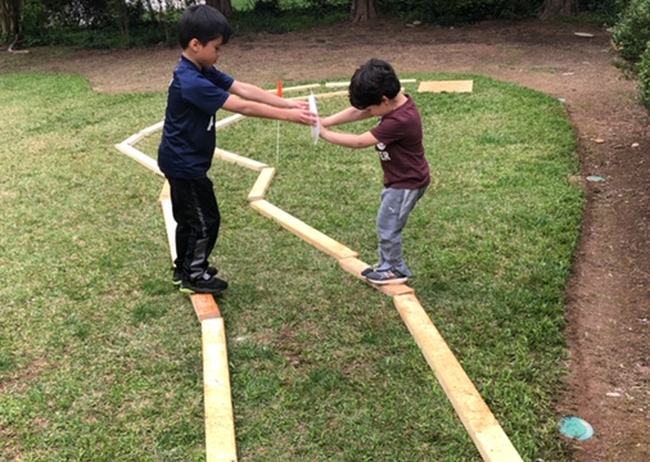 DIY Obstacle Courses for Kids: Balancing Act Two kids balancing on narrow beams, holding a plate between them
