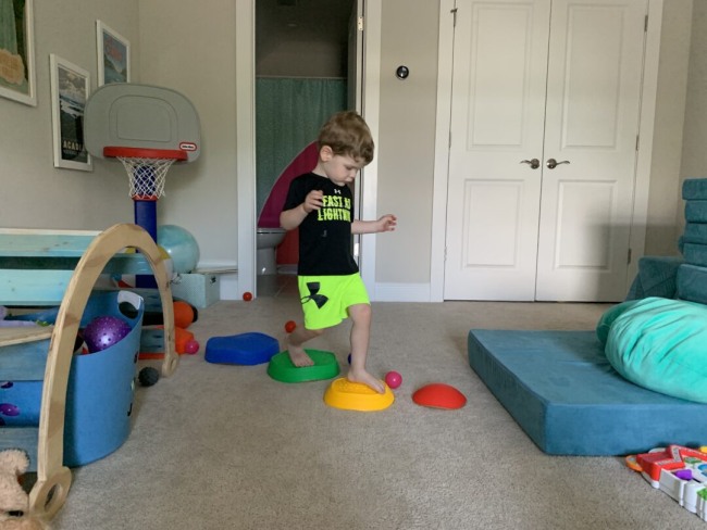 DIY Obstacle Courses for Kids: Indoors A toddler completing an indoor obstacle course by jumping across colored plastic stepping stones