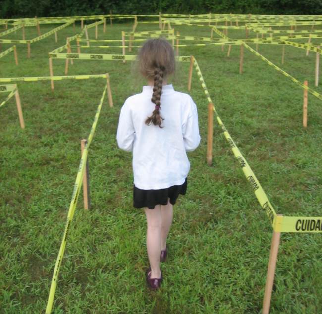 DIY Obstacle Courses for Kids: Maze Child standing at the beginning of a maze made of CAUTION tape strung from stakes