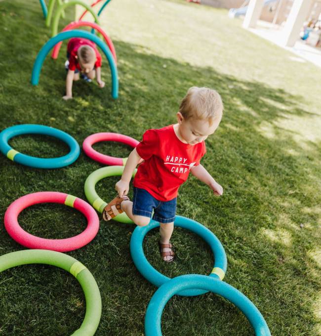 DIY Obstacle Courses for Kids: Pool Noodles Toddlers climbing under hoops and through circles made of pool noodles in a DIY obstacle course for kids