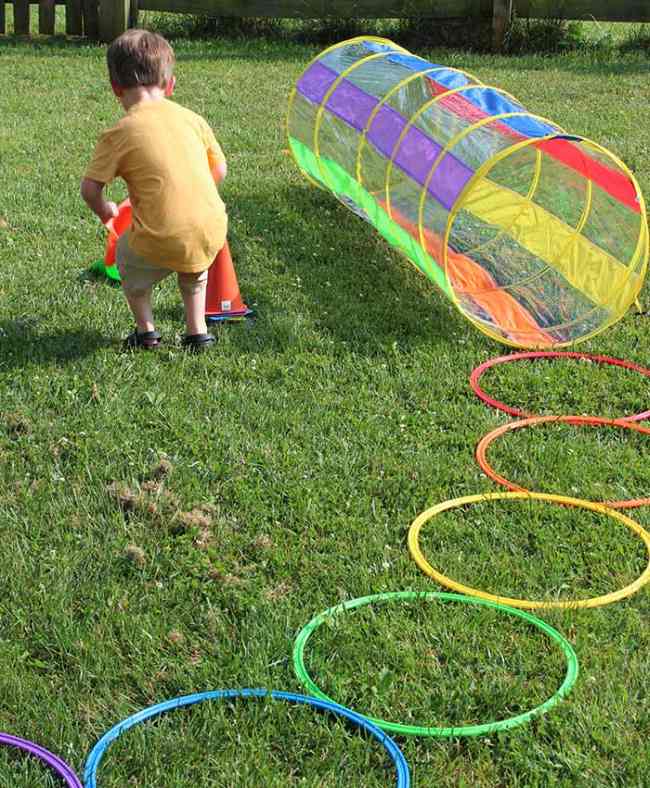 DIY Obstacle Courses for Kids: Rainbow Child setting up colorful plastic cones as part of a rainbow-themed obstacle course in this example of obstacle courses for kids