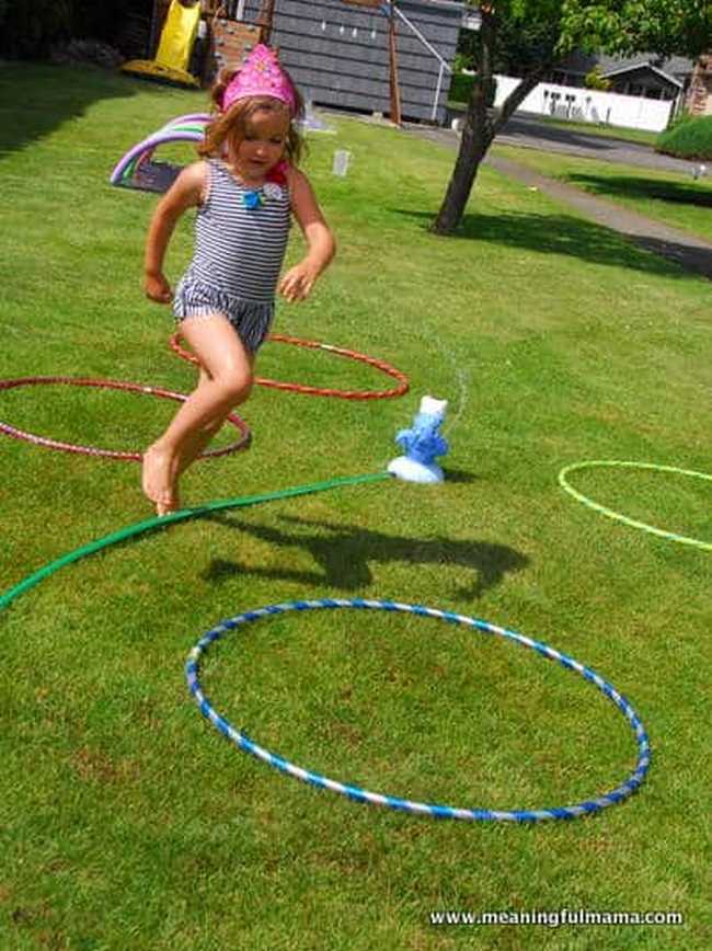 DIY Obstacle Courses for Kids: Water Little girl in a bathing suit running through a backyard obstacle course with sprinklers and other water features in this example of obstacle courses for kids