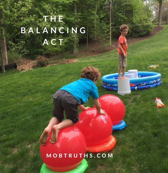 DIY Obstacle Courses for Kids: Wipeout Child crawling over exercise balls balanced on inflatable rings, as part of a Wipeout themed obstacle course