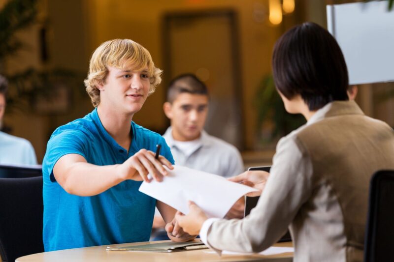 teen-job-interview Teen handing his resume to an employer during an interview