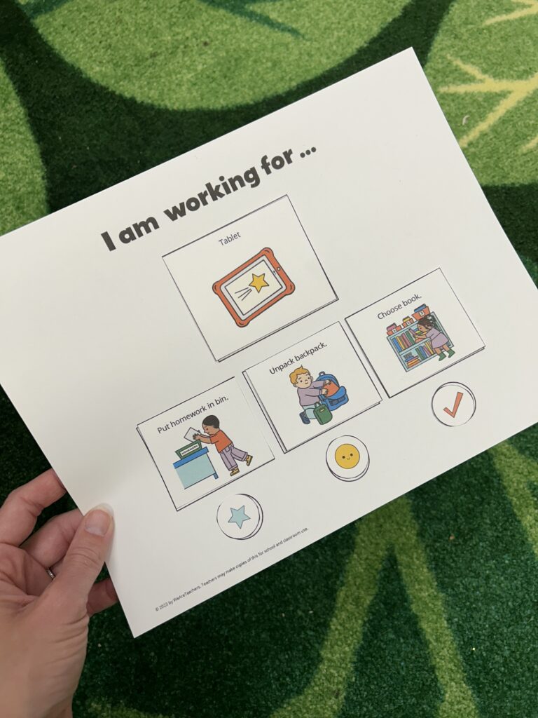 Hand holding work-reward board visual schedule.