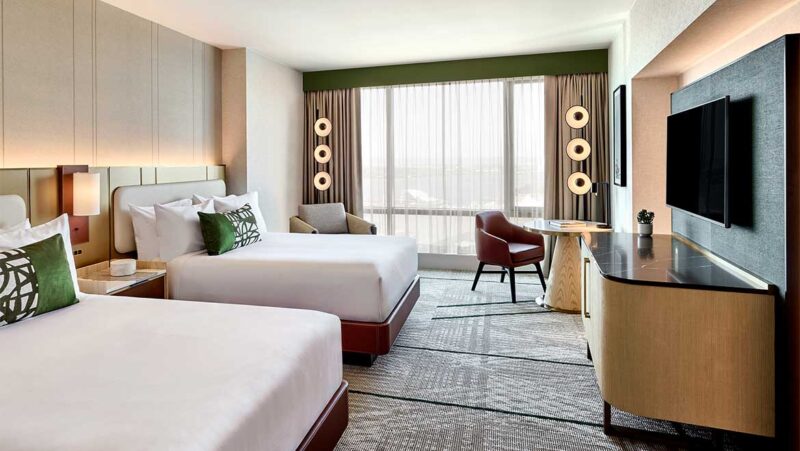Hotel room with two white beds and side table with television