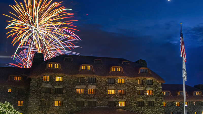 Large building with American flag post and a firework exploding in the sky