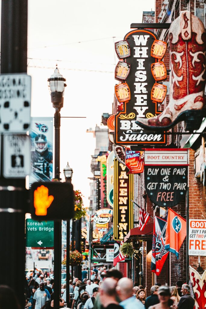 Sidewalk with crowded people and many storefront signs and lights