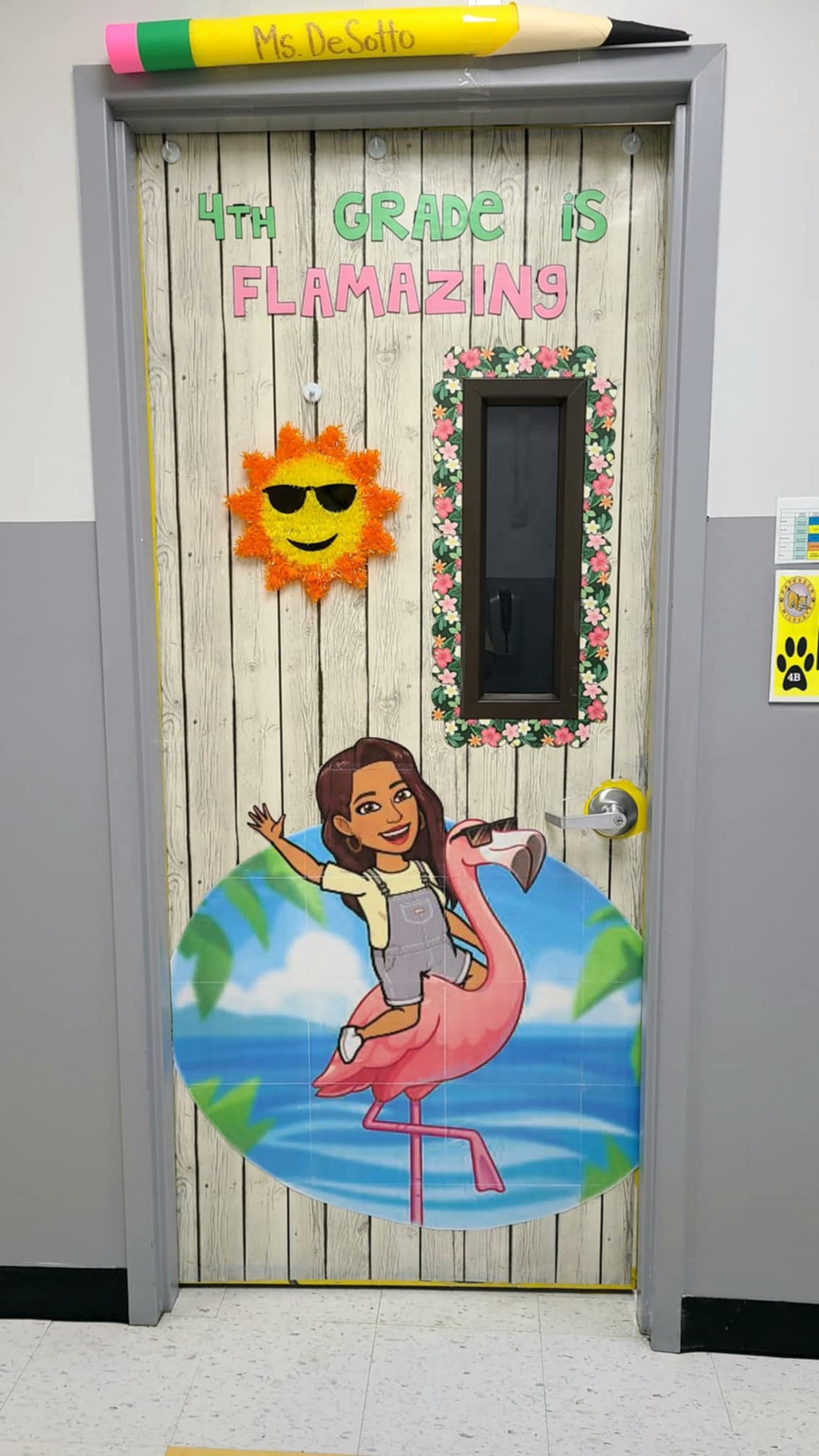 A door says 4th grade is flamazing and features a girl riding a flamingo and a sun with a smiley face.