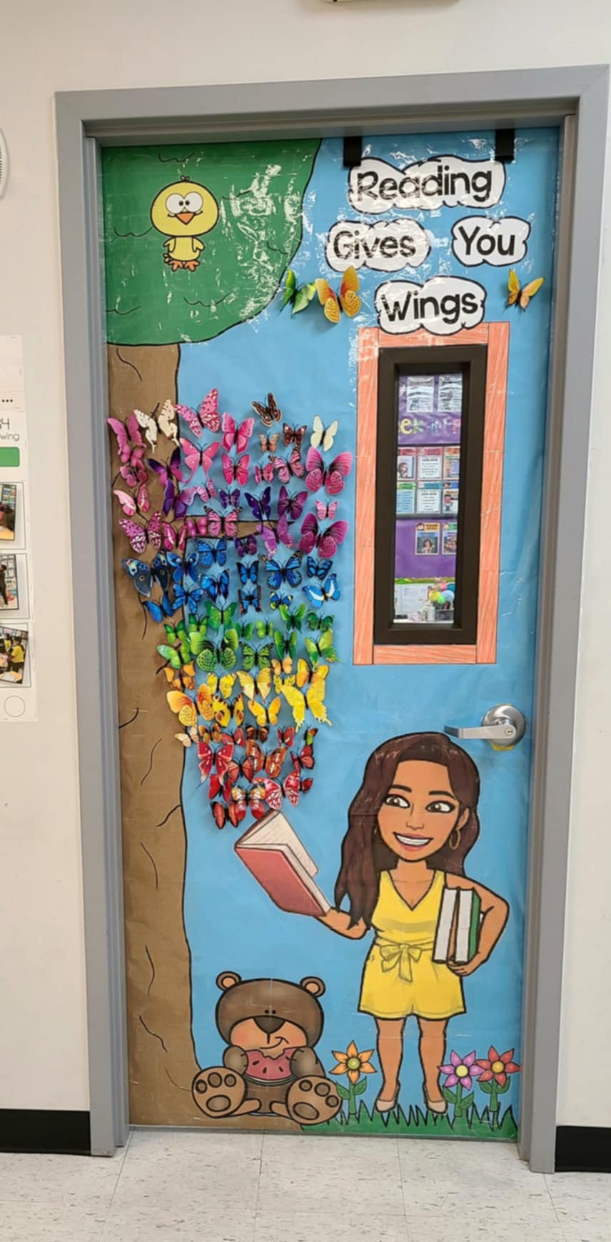 A door says Reading gives you wings. It features a girl reading a book that opens up to a bunch of butterflies.