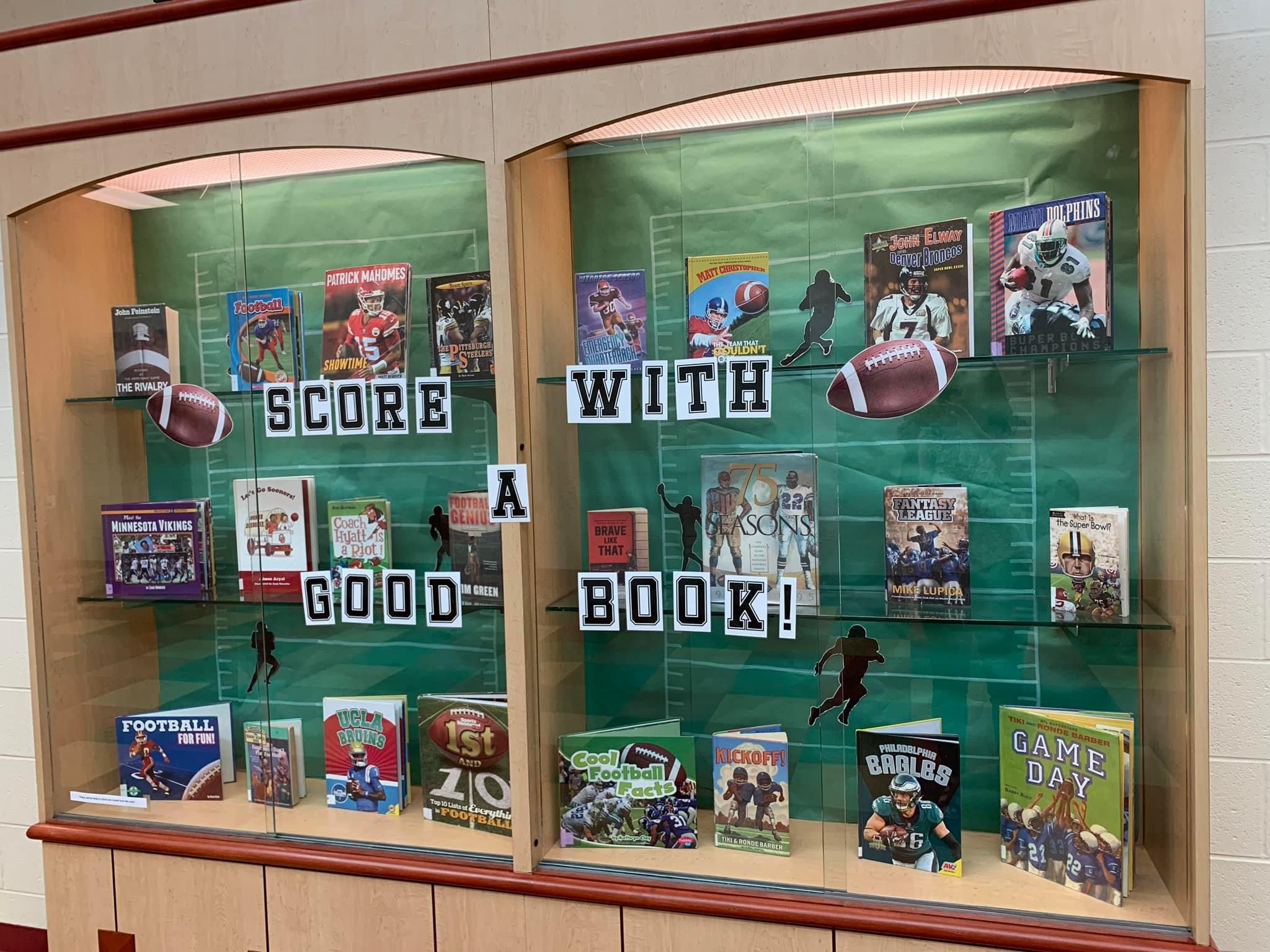 Score-With-Amy-Brownlee A display case cover says Score with a Good Book and has a bunch of football books