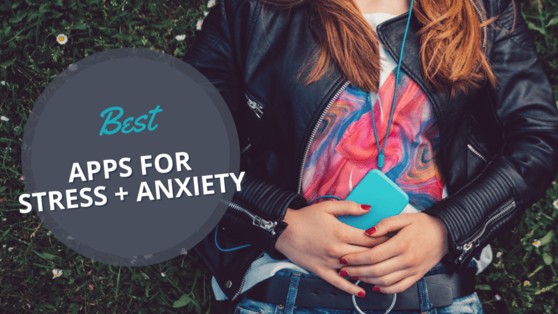 Anxiety Apps Teen girl laying on grass listening to best apps for anxiety and stress on headphones using smart phone.