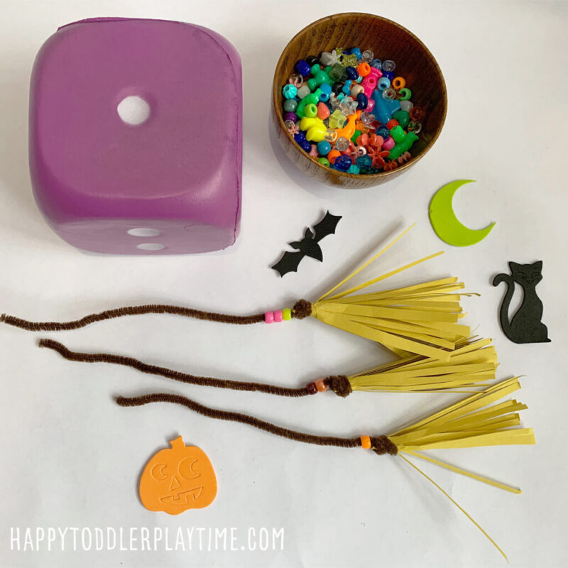 beaded-witch-broom A beading activity laid out with witch's brooms, a bowl of beads and a foam die