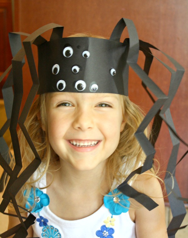 spider-headband A smiling girl wears a spider headband made from black construction paper and many googly eyes