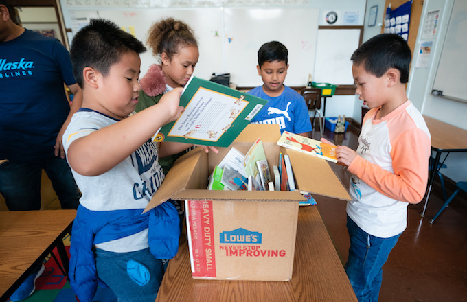 book-donation-project Students gathered around a box of books checking out what's inside