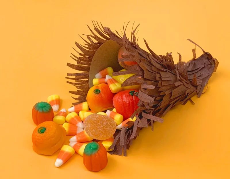 candy-cornucopia A tiny paper cornucopia made from brown fringed tissue paper with candy corn spilling out