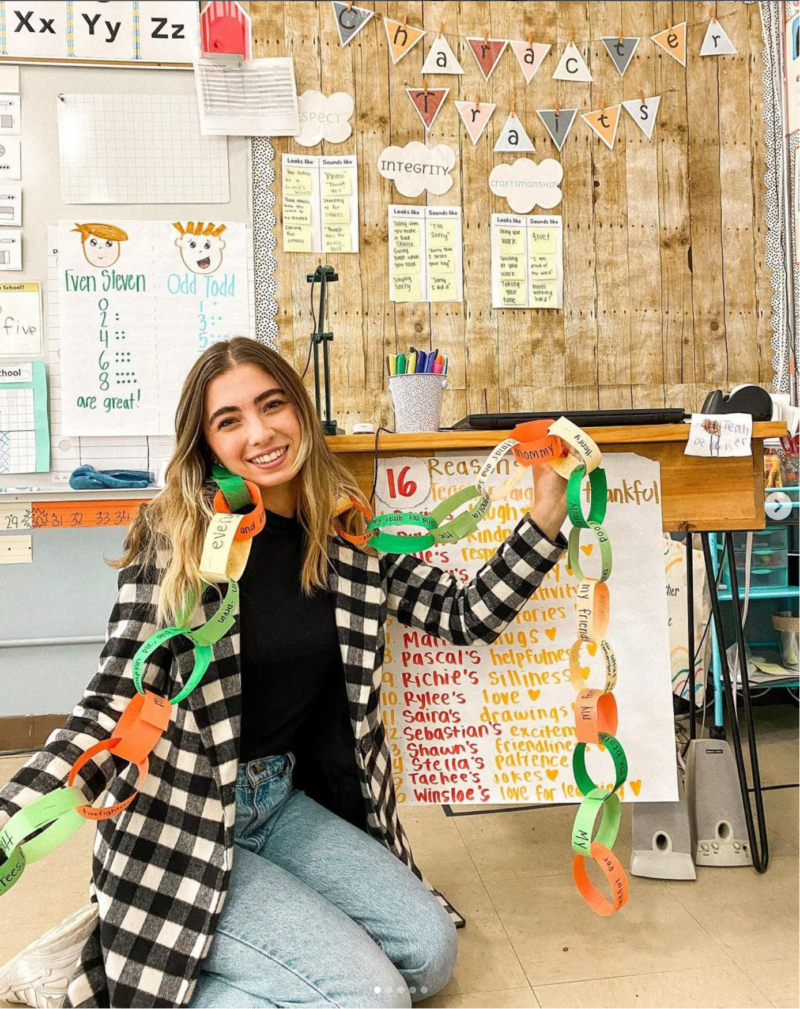Gratitude Chain Teacher sitting on the floor of classroom holding a paper gratitude chain.