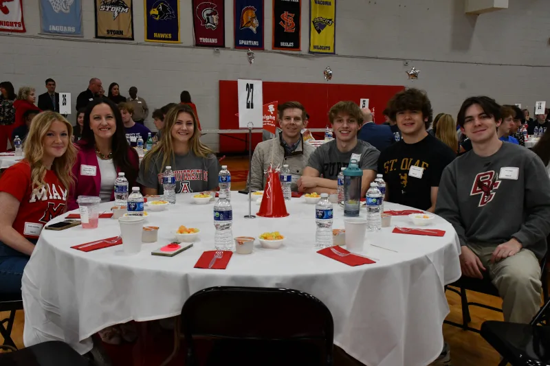 senior-night Senior students and their parents sit at a table covered with a white tablecoth