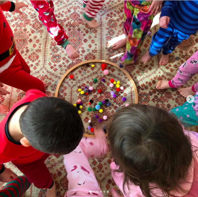 Children play a game trying to pick up pom poms with their toes as an example of Pajama Day ideas and activities