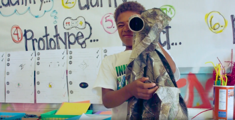DIY invention A young boy holds a homemade innovation made from cardboard and paper as an example of invention ideas for kids
