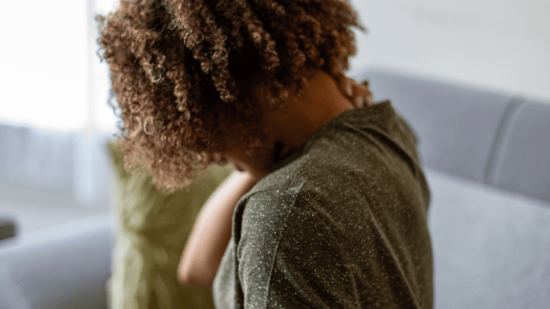 7 Signs You’re Teaching in a “Sick School” Black woman with her back facing us as she rubs her neck in discomfort possibly caused by working in a building with poor air quality