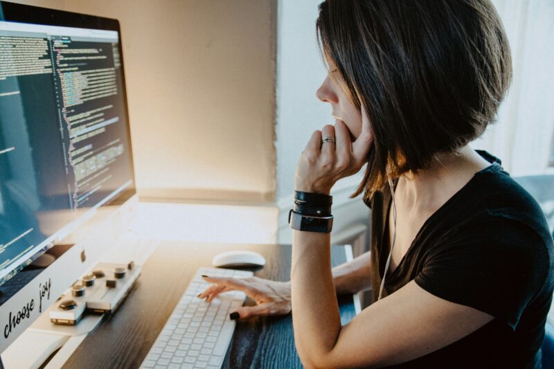 A blockchain developer writes code sitting at a computer
