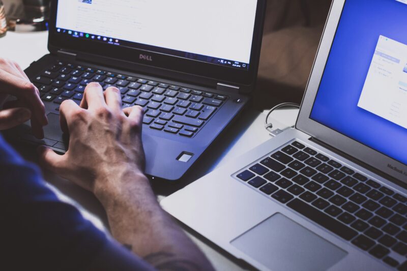 A person uses one laptop while another sits nearby