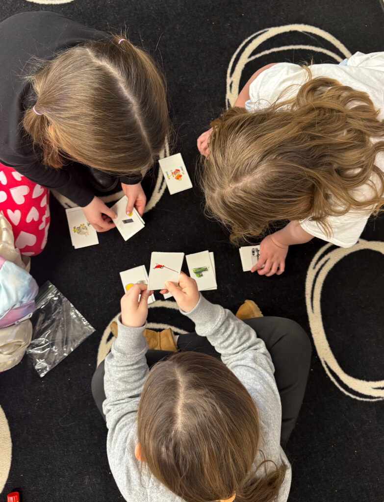 children playing with activity cards image of the tops of three children's heads playing with activity cards