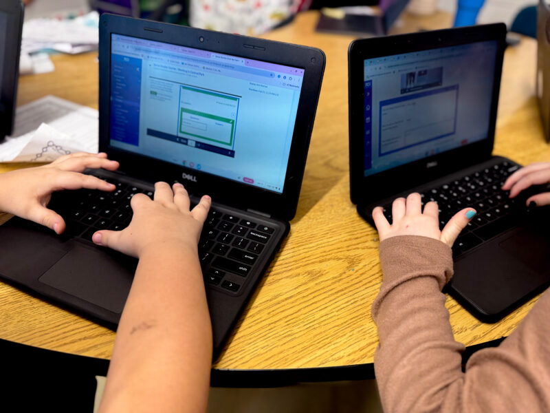kids on their laptops two kids hands typing on two laptops