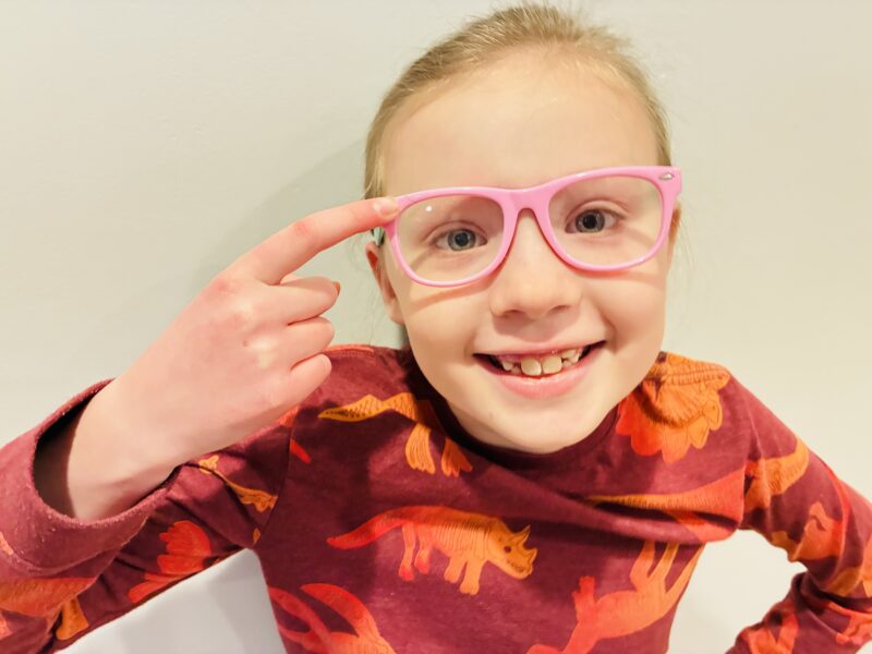 a student wearing pink glasses and pointing to them